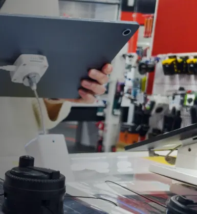 electronics on display in the foreground seen from behind with a woman demoing some in the background