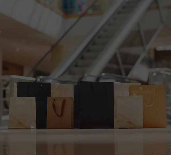 Shopping bags lined up at the bottom of an escalator at the mall