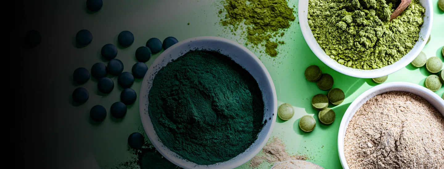 Different colored nutritional supplement powders in bowls and nutritional tablets shot from overhead