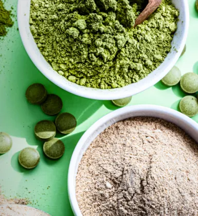 Different colored nutritional supplement powders in bowls and nutritional tablets shot from overhead