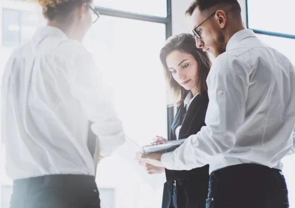 Three colleagues convening around a computer