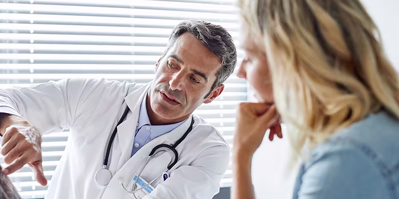 A doctor explaining something to a patient using a tablet