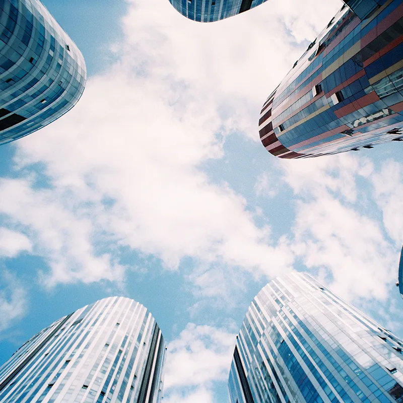 Upward view of skyscrapers against a blue sky with clouds
