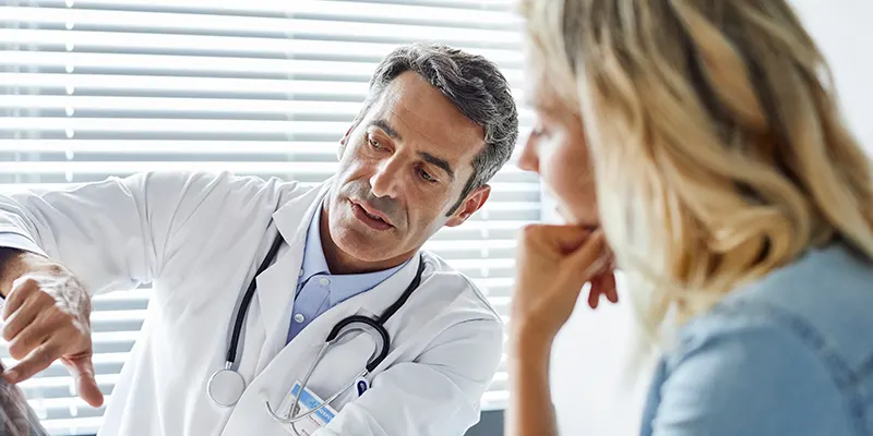 A doctor explaining something to a patient using a tablet